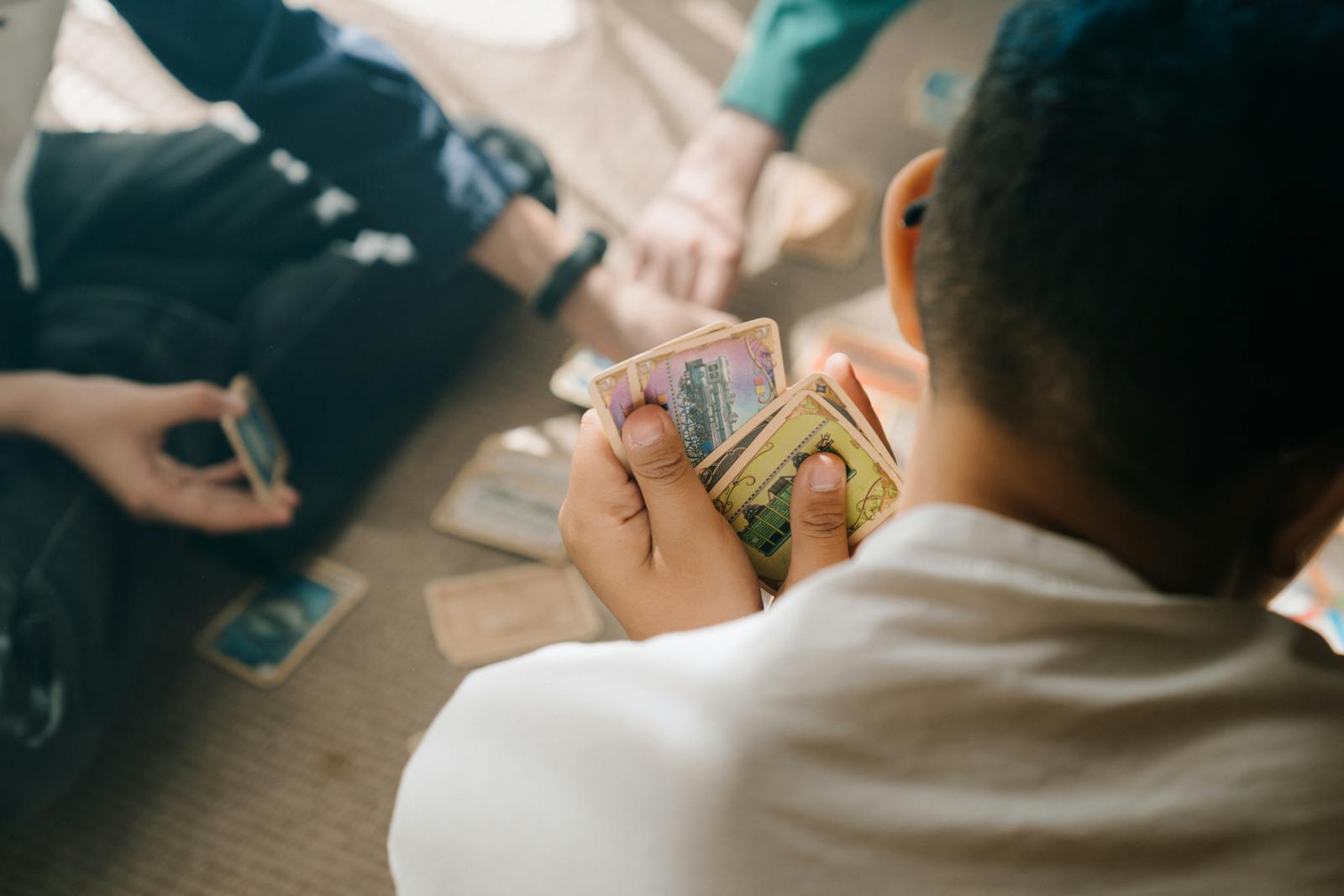 Three children engaged in a strategic card game session, focusing intently on their hands.