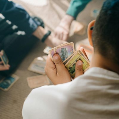 Three children engaged in a strategic card game session, focusing intently on their hands.